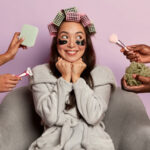 Smiling Woman Applies Eye Patches Hair Curlers Surrounded By Many Beauticians 1